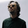 L'auteur-compositeur-interprète Philippe B avec des lunettes de soleil. Le regard vers le haut.
