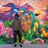 Jimmy Baptiste pose devant un mur où il a peint une oeuvre.