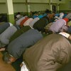 Des hommes agenouillés, têtes baissées faisant la prière.
