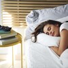 Une femme dort paisiblement sur un lit dans une chambre. 
