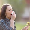Une femme souffre d'une allergie avec des fleurs dans la main gauche. 