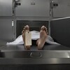 Un corps nu recouvert d'un drap blanc dans le réfrigérateur d'une salle d'autopsie. 