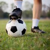 Photo d'un pied posé sur un ballon de soccer sur la pelouse.