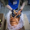 Gros plan sur les mains d’une personne qui sort des carottes d’un sac.