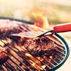 Trois steaks de viande cuisent sur un barbecue au charbon de bois.