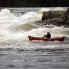 Une personne est à bord d'un canot sur une rivière fortement agitée.