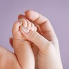 Gros plan sur la main d'une mère qui tient les doigts d'un nouveau-né.
