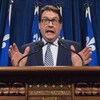 Bernard Drainville parle en agitant les mains derrière un lutrin lors d'une conférence de presse à l'Assemblée nationale. 