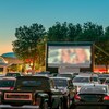 Des voitures stationnées devant un écran de cinéma en plein air.