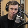 Un homme avec des écouteurs parle dans un micro dans un studio de radio. 