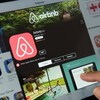 Un aperçu de l'application Airbnb sur une tablette où l'on voit le logo et une photo de piscine. 