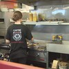 Une jeune femme travaille au gril dans un casse-croûte.