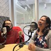 Deux femmes vêtues de couleurs vives et bigarrées rient dans un studio de radio