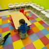 Deux enfants dans une salle aux murs et au sol colorés et avec des chaises pour enfants. 