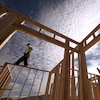 Un travailleur debout sur la structure d'une maison en construction.