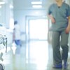 Concept d'environnement de travail stressant : une infirmière marche d'un pas pressé dans un corridor d'hôpital.  