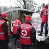 Des membres du Comité international de la Croix-Rouge en Ukraine transfèrent un chargement de vivres d'un camion dans une camionnette militaire.