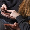 Plan rapproché des mains de deux adolescentes avec leur téléphone cellulaire entre les mains. 