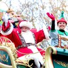 Le Père Noël et un lutin qui saluent la foule dans le chariot du Père Noël. 