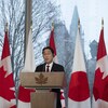 Deux hommes se tiennent côte à côte lors d'une conférence de presse. Derrière eux, des drapeaux japonais et canadiens. 