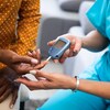 Une infirmière fait un test de glucose à un patient. 