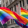 Des drapeaux de la fierté LGBTQ+ en avant d'un bâtiment lors d'une manifestation.