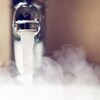 De l'eau coule d'un robinet pendant que de la vapeur monte.