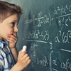 Un enfant devant un problème mathématique sur un grand tableau noir.