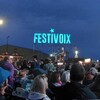 Une enseigne lumineuse du FestiVoix de Trois-Rivières et une foule devant une scène.