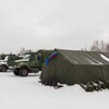 Un grande tente aux côtés de trois camions de l'armée canadienne.