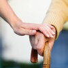 Une préposée aux soins tient la main d'une personne âgée.