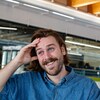 Une personne sourit et porte la main à son front.