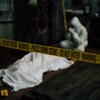 Une scène de crime avec un ruban jaune de la police. Sur le sol, un corps recouvert d'un drap. 