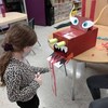 Une petite-fille termine de fabriquer une tête de dragon en carton.