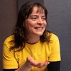 Vêtue de jaune, la chef sourit en discutant.