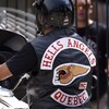 Un homme est sur sa moto avec une veste arborant une tête de mort ailée, symbole des Hells Angels