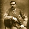 Le bras appuyé sur le dossier d'une chaise, Arthur Conan Doyle pose en complet veston cravate.