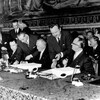 Des hommes signent un traité sur une longue table protocolaire.