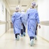 Des infirmières vues de dos marchent dans le corridor d'un hôpital.  