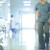 Une infirmière marche d'un pas pressé dans un corridor d'hôpital.  
