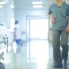 une infirmière marche d'un pas pressé dans un corridor d'hôpital.  