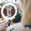 Une influenceuse souriante installe son téléphone portable et filme un vlogue dans un salon.