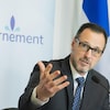 Un homme assis à une table parle en gesticulant lors d'un point de presse du gouvernement du Québec. 