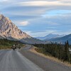 deux motos sur une route de gravier avec au loin des forets et des montagnes