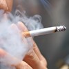 Plan rapproché de la main d'un fumeur tenant une cigarette allumée.