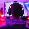 Un homme portant un casque d'écoute joue à un jeu vidéo sur un écran d'ordinateur.