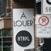 Pancarte de logement à louer entre les panneaux de stationnement sur une rue de Montréal.