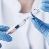 Une personne remplit une seringue à partir d'une fiole de vaccin.