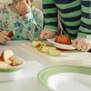 Deux enfants coupent des pommes sur une table. 