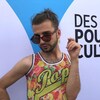 Xavier Gould pose avec des lunettes de soleil devant un panneau avec le libellé « Des ailes pour la culture »